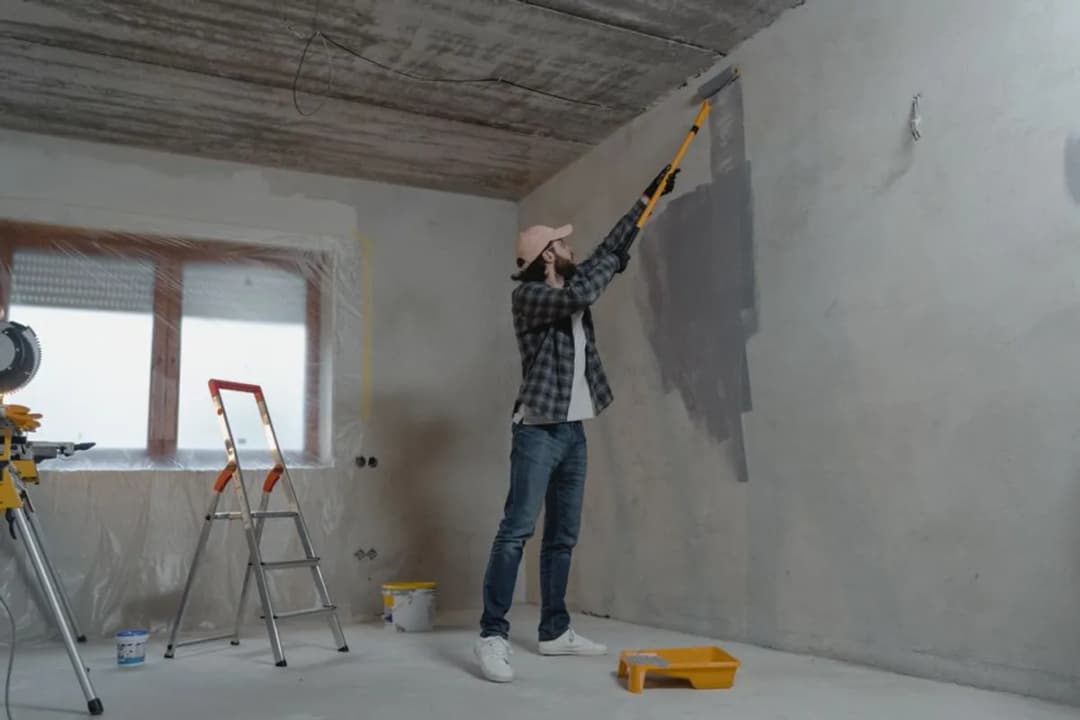 Pintor aplicando pintura en una pared interior